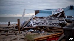 A police officer walks past the remnants of a home leveled by Hurricane Matthew after it hit the tiny beach community of Edisto Beach, South Carolina, Oct. 8, 2016. 