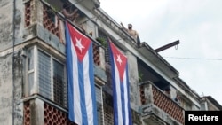 Un hombre cuelga una bandera cubana para tapar las ventanas de la casa de Yunior García, actor, dramaturgo y líder del grupo Archipiélago, en La Habana, el 14 de noviembre de 2021.