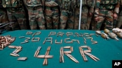 Indian army soldiers stand next to the arms and ammunition recovered near the bodies of suspected rebels after a gunbattle at an army base in Prang, northeast of Srinagar, India, Aug. 30, 2013.