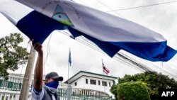 Un nicaragüense residente en Costa Rica ondea una bandera nacional durante una manifestación frente a la Corte Interamericana de Derechos Humanos (CIDH) en San José, el 27 de agosto de 2021, exigiéndole que interfiera contra la detención de políticos opositores en su país.