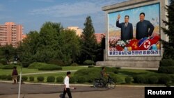 지난달 북한 평양에서 주민들이 김일성 전 주석과 김정일 전 국방위원장 그림 옆으로 지나가고 있다. 