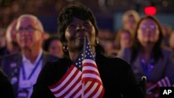 FILE - Superdelegate Margie Woods of Will County, Ill., listens to Michelle Obama, wife of then-Democratic presidential candidate Barack Obama, speak during the Democratic National Convention in Denver, Aug. 25, 2008.