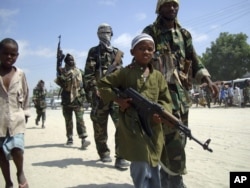 FILE - A young boy leads hard-line Islamist al-Shabab fighters as they conduct military exercises in northern Mogadishu's Suqaholaha neighborhood, Somalia.
