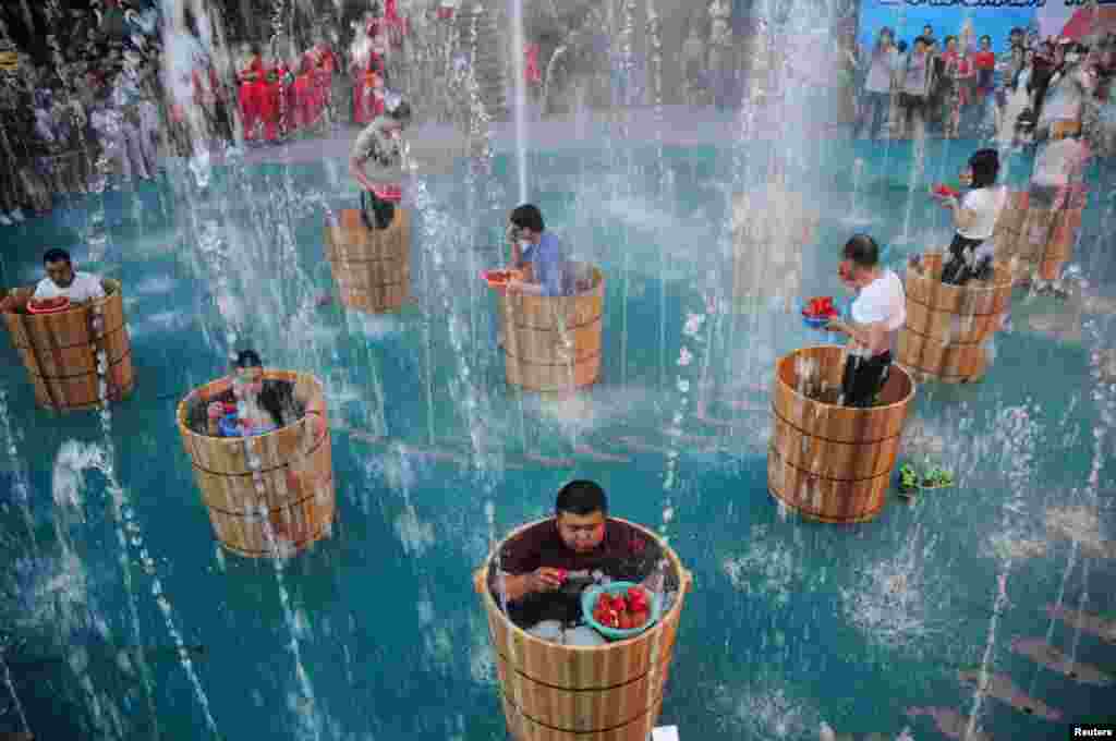 Para peserta makan cabai seraya mandi di air es selama kompetisi makan cabai di Hangzhou, provinsi Zhejiang, China, 20 Juli 2016.