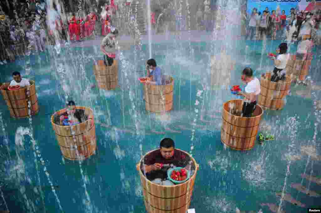 Participants eat chili as they bath in ice water during a chili eating competition in Hangzhou, Zhejiang province, China, July 20, 2016.