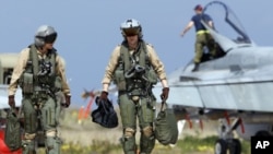 Two CF-18 pilots from Canadian Forces 425 Tactical Fighter Squadron in Bagotville, walk across the tarmac at the Birgi NATO Airbase in Trapani, Sicily, March 24, 2011. Canada has deployed six CF-18 (CF-188) fighter jets to enforce the no-fly zone over Lib