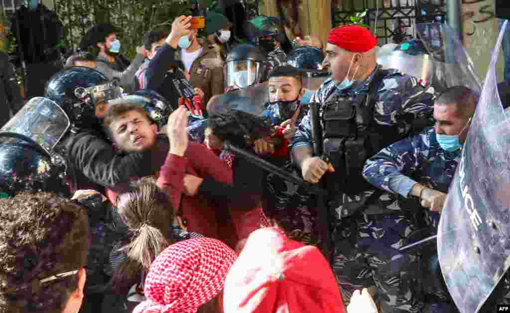 A policeman chokes a protester during a demonstration outside the entrance of the American University of Beirut, Lebanon, against the adjustment of the dollar rate for new tuition fees.