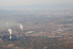 FILE - Smoke and steam rise from towers at the coal-fired Urumqi Thermal Power Plant in Urumqi in western China's Xinjiang Uyghur Autonomous Region, April 21, 2021.