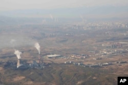 FILE - Smoke and steam rise from towers at the coal-fired Urumqi Thermal Power Plant in Urumqi in western China's Xinjiang Uyghur Autonomous Region, April 21, 2021.