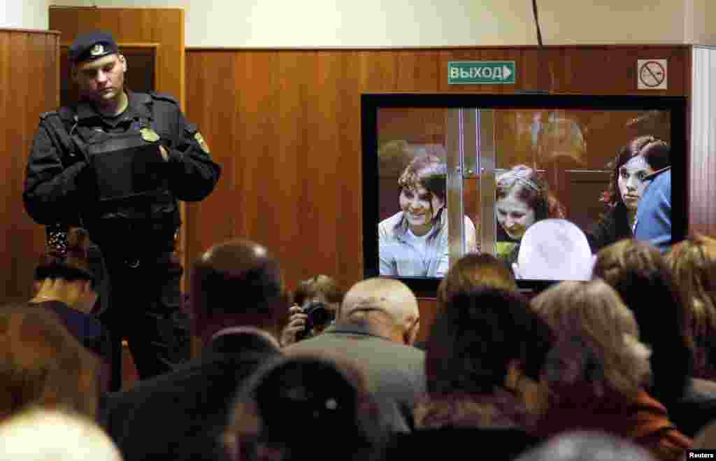 A bailiff stands in a room as people watch a live broadcast of a court hearing on members of the punk band in Moscow October 10, 2012.