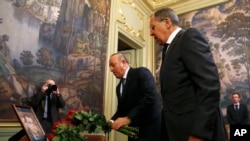 Russian Foreign Minister Sergei Lavrov, right, and Turkey's Foreign Minister Mevlut Cavusoglu offer flowers in memory of Russian Ambassador to Turkey Andrei Karlov, before their talks on Syria in Moscow, Russia, Dec. 20, 2016.