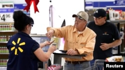 Don Wood checks out at a register at Walmart as the store prepares for Black Friday in Los Angeles, California, Nov. 24, 2014.