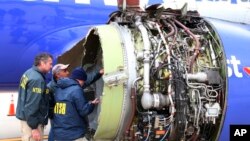 National Transportation Safety Board investigators examine damage to the engine of the Southwest Airlines plane that made an emergency landing at Philadelphia International Airport, April 17, 2018. The engine blew at 32,000 feet. 