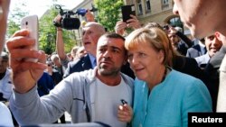 Kanselir Jerman Angela Merkel disambut meriah oleh pengungsi Suriah dan dijuluki 'Mama Merkel' saat berkunjung ke pusat registrasi migran di distrik
Spandau, Berlin hari Kamis (10/9).