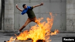 FILE - A Palestinian protester throws a stone during clashes with Israeli soldiers and border policemen in the West Bank city of Hebron, Feb. 24, 2013