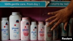 Seorang pekerja menutup lemari berisi botol-botol bedak tabur untuk bayi produksi Johnson & Johnson di sebuah toko obat di Kalkuta, India, 20 Desember 2018. (Foto: Reuters)