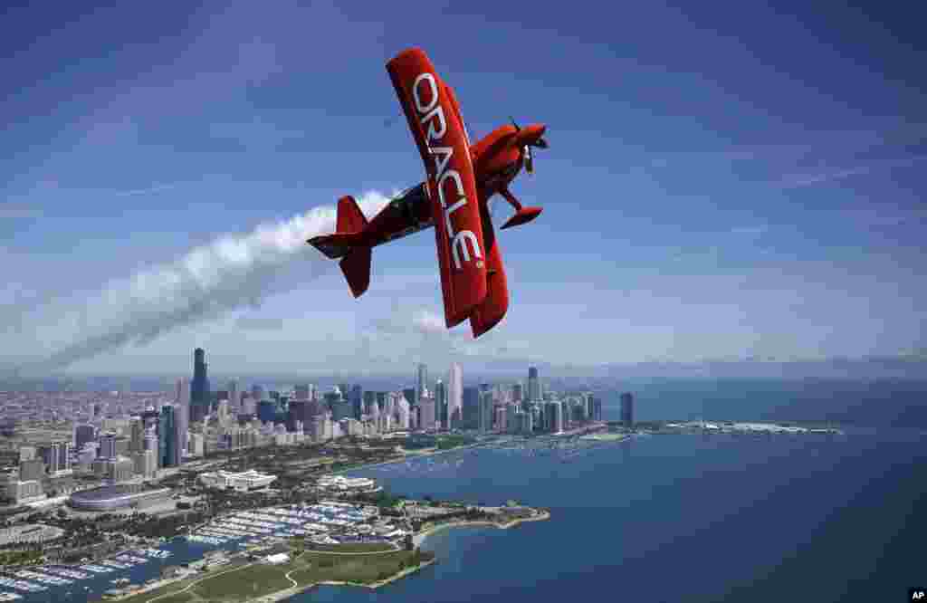 Aerobatic pilot Sean D. Tucker flies in the two-seat Oracle Extra airplane over downtown Chicago skyline, Illinois, USA.