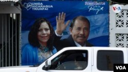 Una camioneta pasa por delante de un cartel que promociona a Daniel Ortega y su esposa Rosari Murillo como pareja presdencial el 8 de noviembre de 2021. Foto: Houston Castillo. VOA.