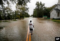 Helen McKoy walks down a flooded street in her neighborhood as Florence continues to dump heavy rain in Fayetteville, N.C., Sept. 16, 2018.