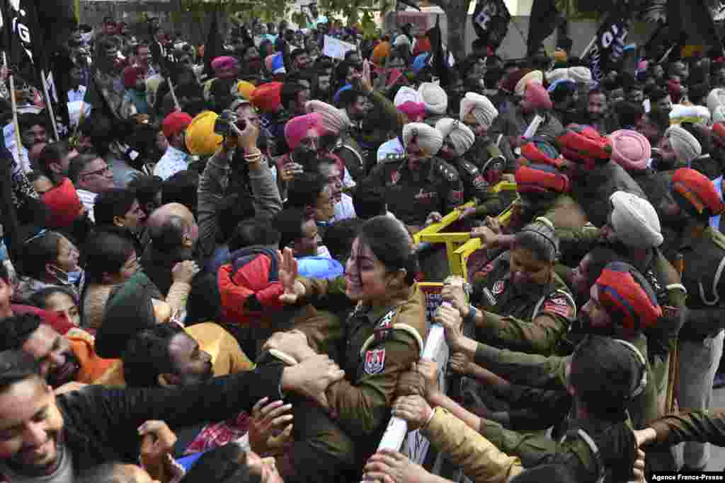 Protesting workers from the National Health Mission try to cross a police barricade during a protest march towards the residence of Punjab Deputy Chief Minister in Amritsar, India.