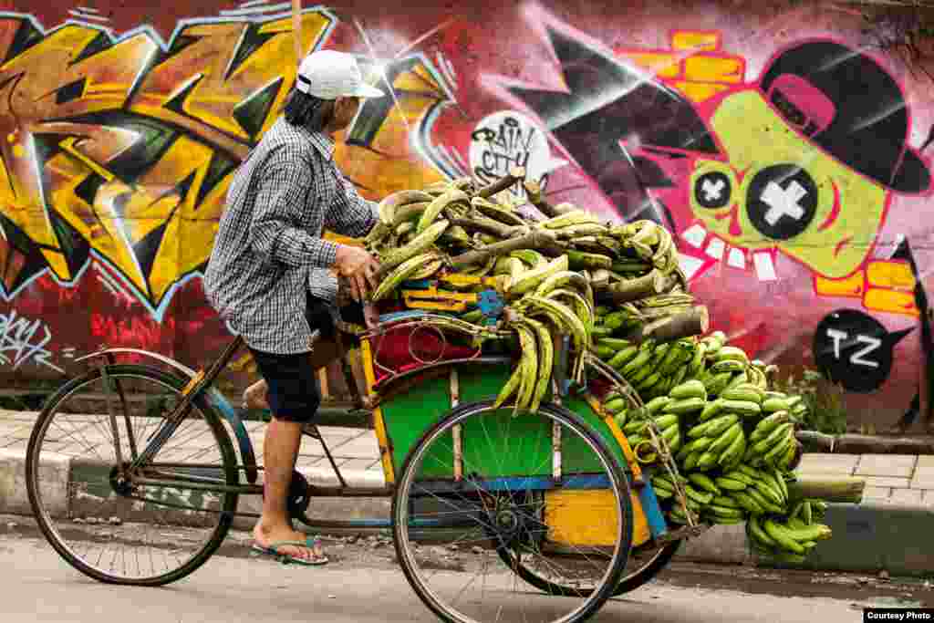 A man rides a trishaw loaded with bananas in Bogor fruit market in Bogor, West Java, Indonesia (Photo by Davide Rosa/VOA reader)