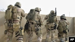 A team of U.S. Navy SEALs fires on insurgents from a rooftop in this April 2006 file photo in Ramadi, Iraq. (AP)