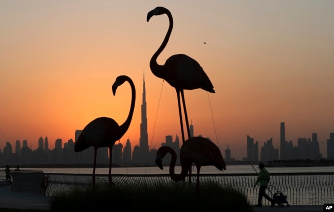 Cakrawala kota dengan latar belakang Burj Khalifa, gedung tertinggi di dunia, dibingkai oleh patung flamingo saat matahari terbenam di Dubai, Uni Emirat Arab, Selasa, 15 Oktober 2019. (Foto: AP/Kamran Jebreili)