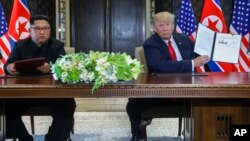 12일 싱가포르 카펠라 호텔에서 도널드 트럼프 미국 대통령이 김정은 북한 국무위원장과 정상회담 공동합의문에 서명한 후 합의문을 들어보이고 있다.