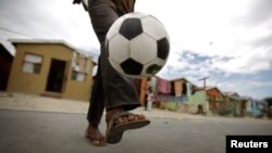 Un gamin joue au football dans les rue du Cap en Afrique du Sud
