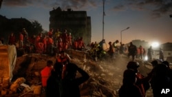 Members of rescue services search for survivors in the debris of a collapsed building in Izmir, Turkey, Monday, Nov. 2, 2020. In scenes that captured Turkey's emotional roller-coaster after a deadly earthquake, rescue workers dug two girls out alive Monda