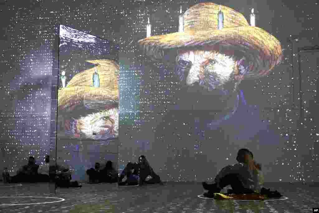 People look at images seen on the wall and reflected in a mirror during a virtual show called &quot;Immersive Van Gogh&quot; at the Lighthouse ArtSpace, in Chicago, Illinois, USA.