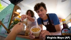 In this In this Sept. 21, 2014 photo, food truck owner Bart Smit holds a container of yellow mealworms during a food truck festival in Antwerp, Belgium. (AP Photo/Virginia Mayo, File)