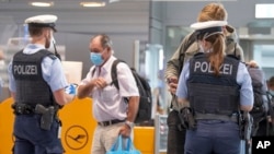 Federal police officers check passengers arriving aboard a flight from Portugal, at Frankfurt airport, Germany, Tuesday June 29, 2021.
