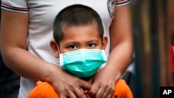 FILE - A child wearing a face mask waits for a COVID-19 test outside a government apartment in Kampung Baru, a traditional Malay village in Kuala Lumpur, Malaysia, April 15, 2020. 