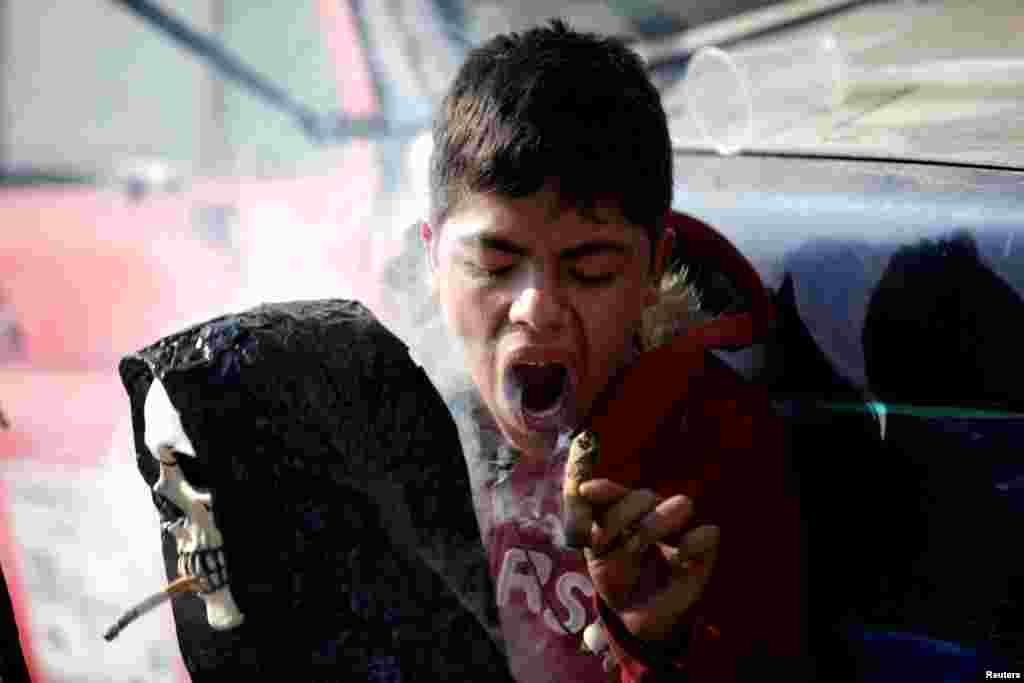 A follower blows smoke from a cigar on a statue of La Santa Muerte (The Saint of Death), a cult figure often depicted as a skeletal grim reaper, as part of a cleansing ritual in Tepito neighbourhood, in Mexico City, Mexico, Jan. 1, 2019.