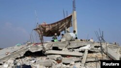 Palestinian children sit atop the remains of their house, which witnesses said was destroyed in the Israeli offensive, during a 72-hour truce in Khan Younis, southern Gaza Strip, Aug. 13, 2014. 