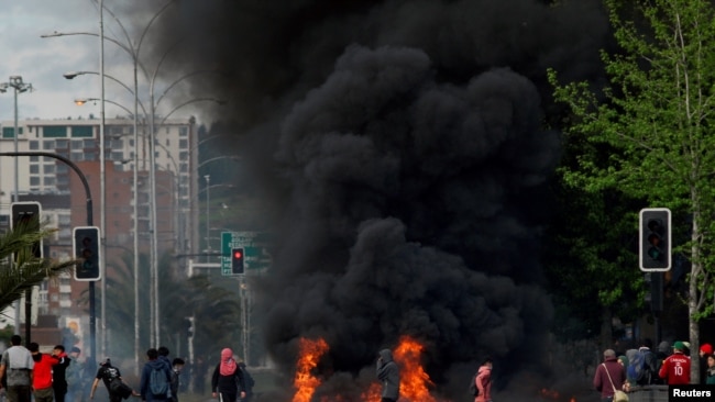 Manifestantes enmascarados junto a una barricada incendiada en Santiago de Chile el 20 de octubre de 2019.