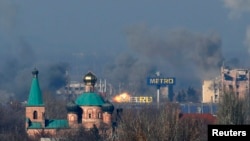 Smoke rises above an old terminal, left, and an administrative building of the airport after the recent shelling during fighting between pro-Russian separatists and Ukrainian government forces in Donetsk, eastern Ukraine, Nov. 9, 2014.