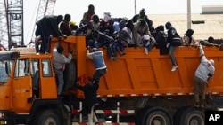 Migrant workers from Africa jump off a truck after arriving in Misrata port during an evacuation operation organized by IOM (International Organization for Migration), April 23, 2011