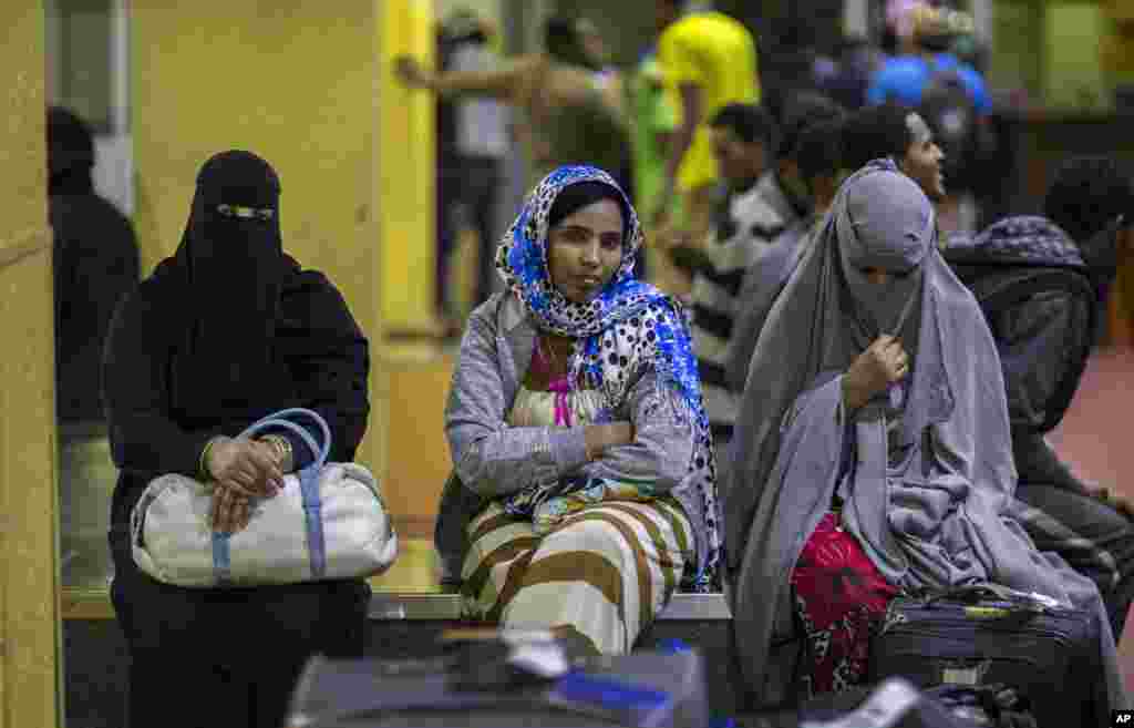 Ethiopian women sit on a luggage conveyor belt as they wait for family members after being deported from Saudi Arabia, at the airport in Addis Ababa, Ethiopia.