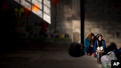 Deux jeunes femmes afghanes attendent d'être enregistrées dans le centre d'inscription de Tabakika, en Grèce, le 15 janvier 2016.