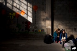 FILE - Two Afghan young women wait to be registered in the Tabakika registration center, Greece, Jan. 15, 2016.