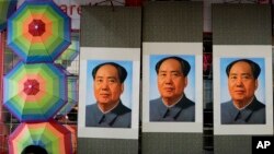 A salesperson sits near posters of the late communist leader Mao Zedong on display for sale at a shop near Tiananmen Square in Beijing, Sept. 9, 2016.