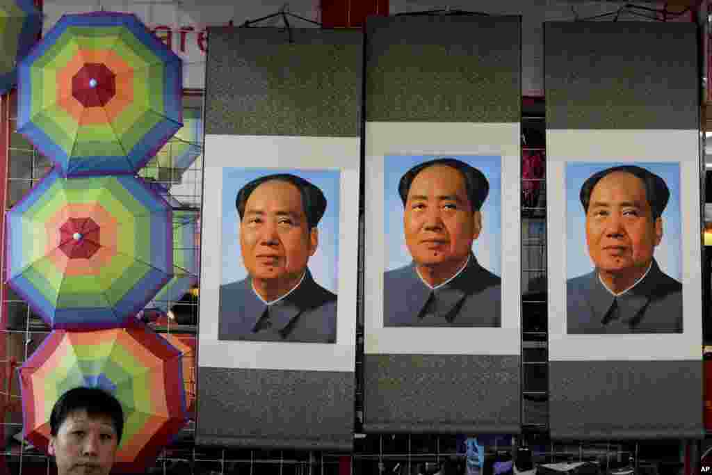 A salesperson sits near posters of the late communist leader Mao Zedong on display for sale at a shop near Tiananmen Square in Beijing. Friday marks the 40th anniversary of the death of the leader who founded the People&#39;s Republic of China in 1949 and ran it virtually uncontested until 1976.