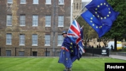 An anti-Brexit protester carries flags opposite the Houses of Parliament in London, Britain, May 10, 2018. 