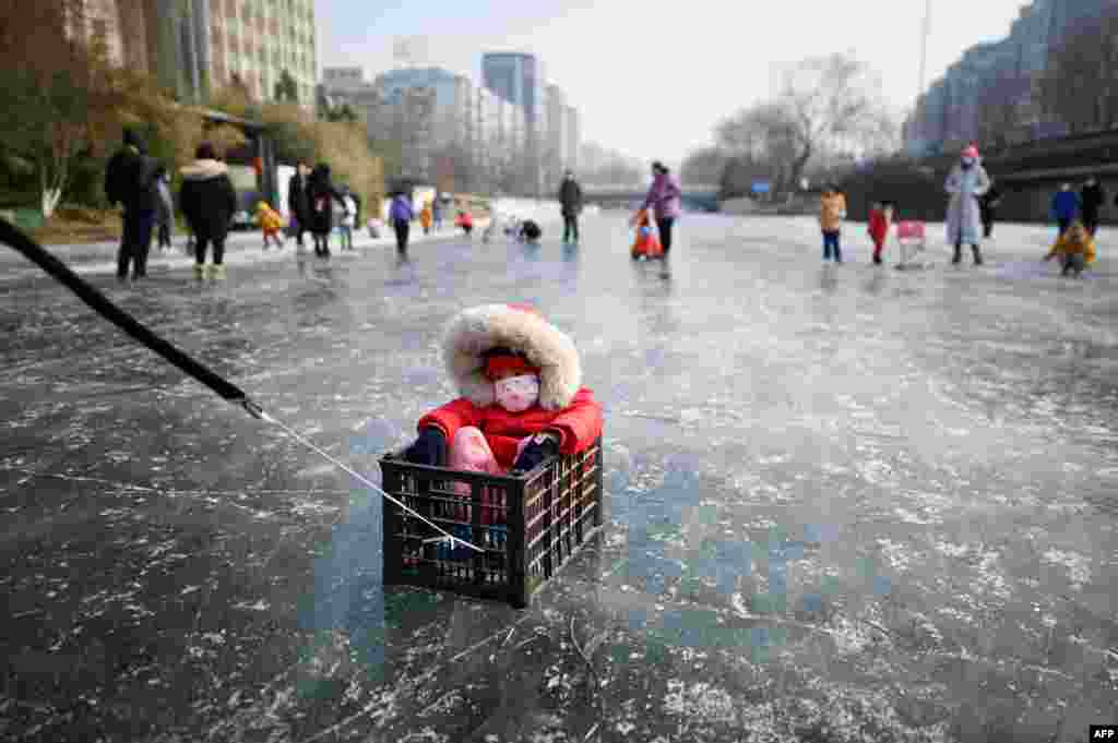 A man, not pictured, pulls a child sitting in a box on a frozen river in Beijing.