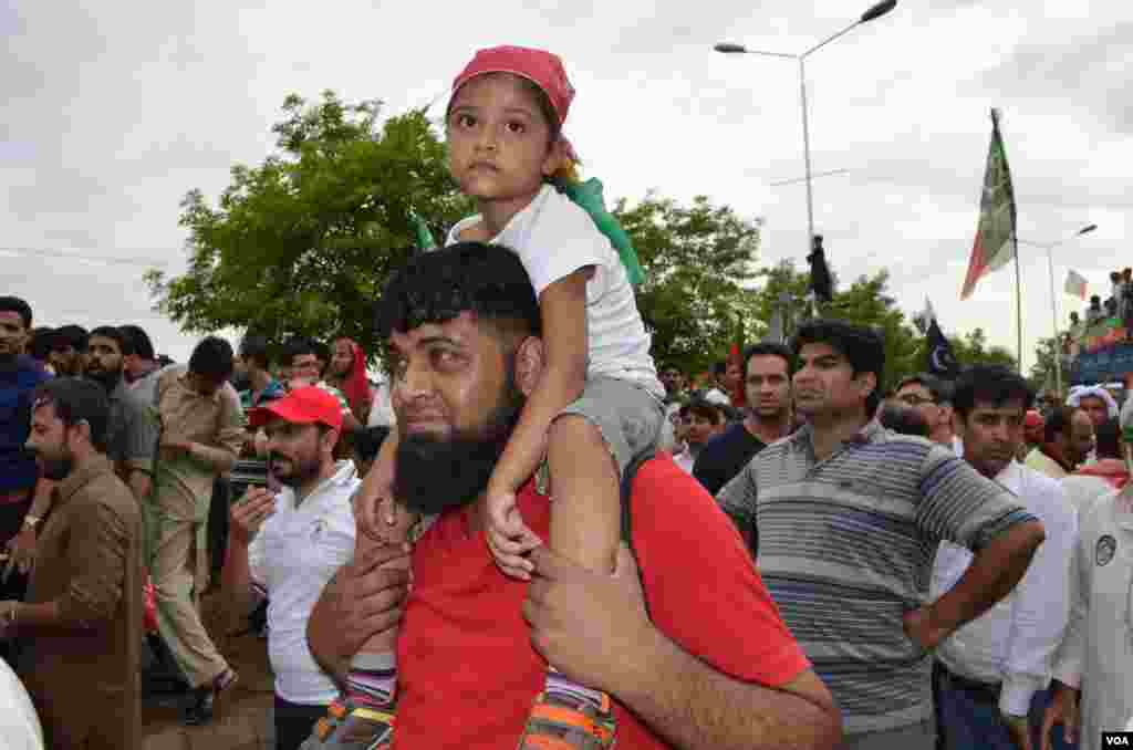 ایک بچہ اپنے والد کے کندھے پر سوار مارچ میں شریک ہے۔