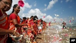 Mujeres esparcen pétalos de flores en las aguas de la Bahía de Bengala durante una ceremonia de oración por las víctimas del tsunami de 2004, a 15 años del desastre, en la playa de Marina en Chennai, India, 26 de diciembre de 2019.