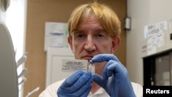 FILE - Professor Adrian Hill, director of the Jenner Institute and chief investigator of the trials, holds a phial containing the Ebola vaccine at the Oxford Vaccine Group Centre for Clinical Vaccinology and Tropical Medicine (CCVTM) in Oxford, England.