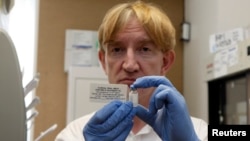 FILE - Professor Adrian Hill, director of the Jenner Institute and chief investigator of the trials, holds a phial containing the Ebola vaccine at the Oxford Vaccine Group Centre for Clinical Vaccinology and Tropical Medicine (CCVTM) in Oxford, southern E